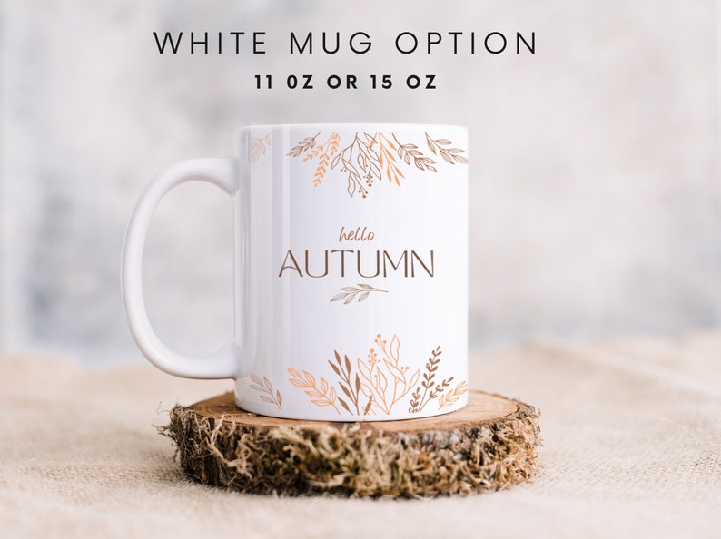 May include: White ceramic mug with a brown and orange floral design and the text "hello autumn". The mug is sitting on a wooden coaster.