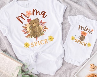 May include: White t-shirts with a brown bear and floral design. The larger shirt says "mama spice" and the smaller shirt says "mini spice".