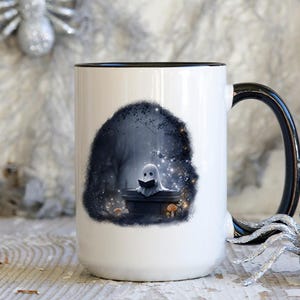 Puede incluir: Taza de cer&aacute;mica blanca con asa y borde negros. La taza presenta una ilustraci&oacute;n caprichosa de un fantasma leyendo un libro en un entorno de bosque oscuro. El dise&ntilde;o incluye setas y estrellas brillantes.