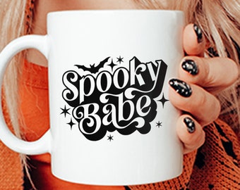 May include: White ceramic mug with a black graphic that says "Spooky Babe" with a bat and stars.
