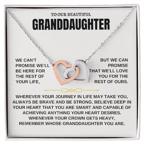 Puede incluir: Un collar plateado con dos colgantes de corazón entrelazados, uno de oro rosa y otro plateado. El collar se presenta en una tarjeta blanca con el texto "TO OUR BEAUTIFUL GRANDDAUGHTER" y un mensaje de amor.