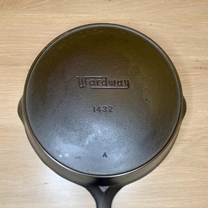 May include: A black cast iron skillet with a long handle. The skillet has the word "Wardway" and the number "1432" embossed on the bottom. The letter "A" is also embossed on the bottom.