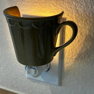 Lámpara de noche con forma de taza de té y borde festoneado verde.