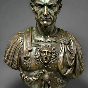 Puede incluir: Un busto de color bronce de un hombre con cabello corto y ondulado, que lleva una coraza adornada con un relieve central de una cabeza de Gorgona y un emblema de águila en la base. La escultura presenta una pátina desgastada con tonos verdes.