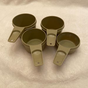 May include: Set of four beige plastic measuring cups with handles.