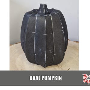 May include: A black oval pumpkin with white markings and the numbers 1 through 5. The pumpkin is sitting on a wooden surface. The text "OVAL PUMPKIN" is at the bottom of the image.