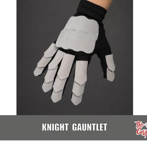 May include: A black glove featuring light gray, layered, scale-like plates covering the back of the hand and fingers. The text KNIGHT GAUNTLET is printed in white below the glove, with The Dodo Cosplay logo in red and white in the corner.