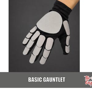 May include: A black glove featuring light gray, rounded rectangular padding pieces attached to the back of the hand and fingers, mimicking a skeletal structure. The text "BASIC GAUNTLET" and "The Dodo Cosplay" are printed at the bottom of the image.