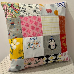 May include: A patchwork pillow with a variety of fabric patterns and colors. The pillow features squares of different fabrics, including floral, animal prints, and text that reads "NICU GRADUATE!" and a penguin. The pillow is a mix of textures and designs.