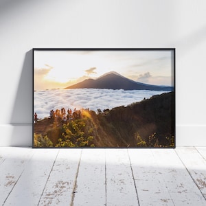 Könnte beinhalten: Ein Panoramablick auf eine Bergkette mit einer Wolkendecke am Fuße. Eine Gruppe von Menschen steht auf einer Klippe und blickt auf die Wolken und Berge. Die Sonne geht hinter den Bergen unter und taucht die Szene in ein warmes Licht.