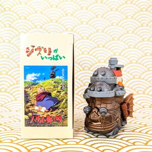 Peut inclure: Une figurine de style steampunk de couleur bronze avec un design d&eacute;taill&eacute;, ressemblant &agrave; un v&eacute;hicule ou une machine. &Agrave; c&ocirc;t&eacute;, une bo&icirc;te avec du texte japonais et une illustration d'une sc&egrave;ne de film. Le fond a un motif de vagues or et blanc.