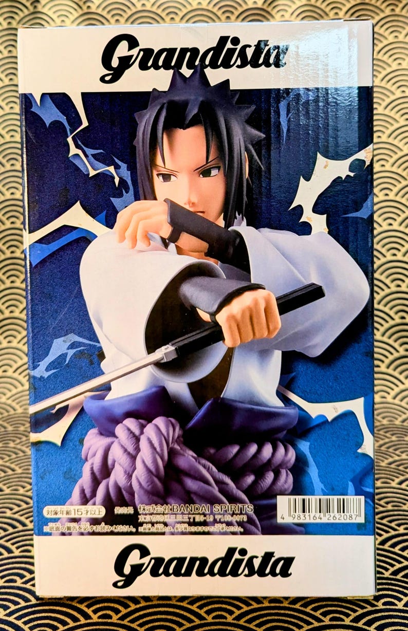 Pode incluir: Figura Grandista de um personagem de anime masculino em um traje branco e azul, segurando uma arma preta. A figura tem cabelo preto e est&aacute; em um fundo azul com desenhos de raios. A caixa tem o logotipo Grandista.