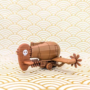May include: A brown toy submarine with a propeller and a skull and crossbones on the side. The submarine is on a gold and white patterned surface.