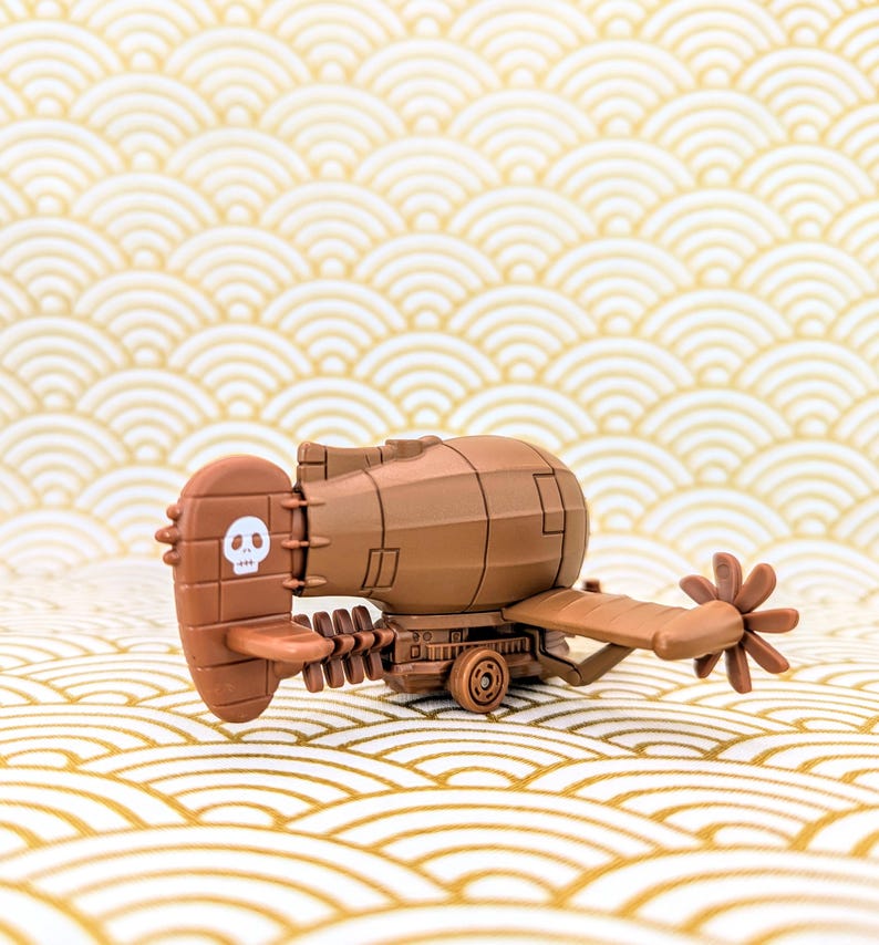 May include: A brown toy submarine with a propeller and a skull and crossbones on the side. The submarine is on a gold and white patterned surface.