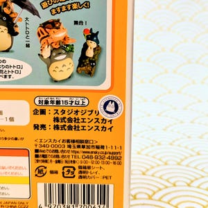 May include: A product box featuring miniature figurines of characters from a Japanese animated film. The box has Japanese text and illustrations of the characters. The figurines are colorful and detailed, with one resembling a large, gray creature.