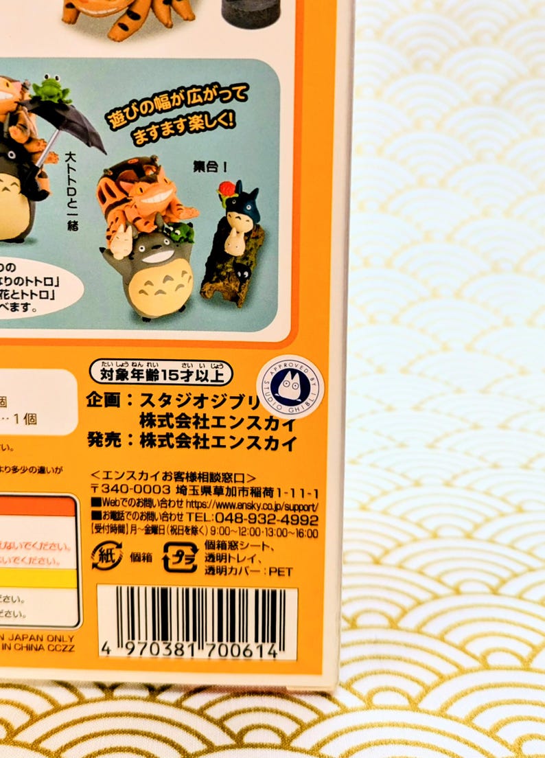May include: A product box featuring miniature figurines of characters from a Japanese animated film. The box has Japanese text and illustrations of the characters. The figurines are colorful and detailed, with one resembling a large, gray creature.