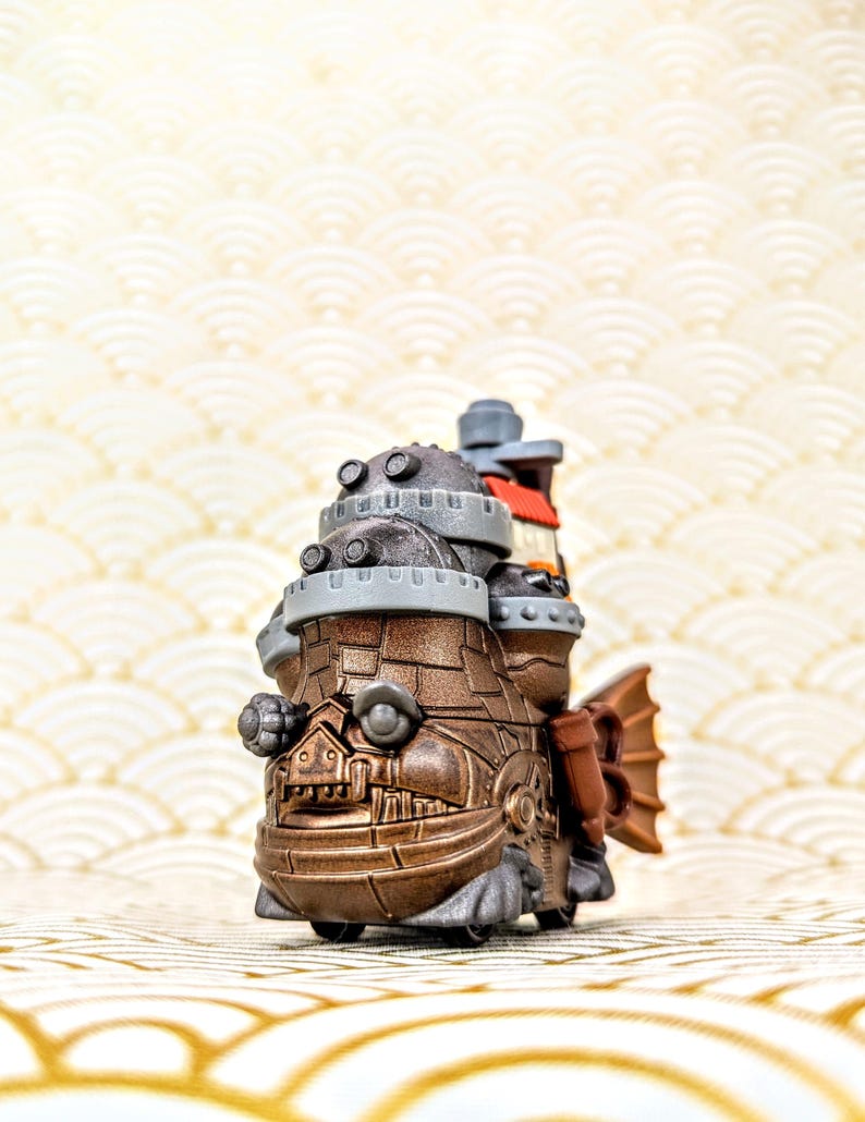 Peut inclure: Un jouet d&eacute;taill&eacute; de style steampunk avec une nageoire caudale en forme de poisson. Le jouet est principalement marron avec des accents m&eacute;talliques, avec plusieurs niveaux avec des d&eacute;tails circulaires et un petit b&acirc;timent au sommet. Le fond a un motif de vagues dor&eacute;es.