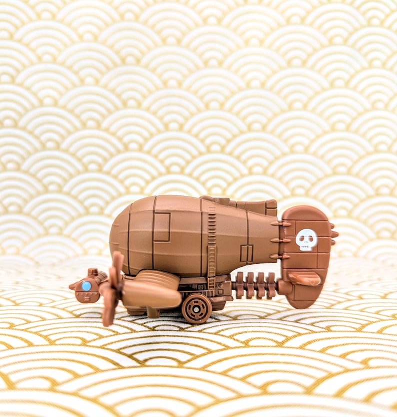 May include: A brown toy airplane with a skull and crossbones on the tail. The airplane has a propeller and wheels.