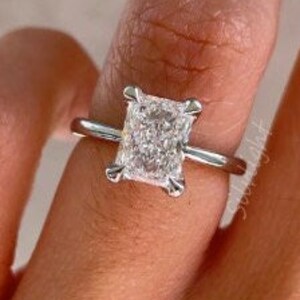 Puede incluir: Un anillo de plata con un gran diamante de forma cuadrada. El diamante está engastado en un sencillo engaste de cuatro garras.
