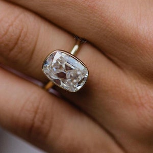May include: A gold ring with a large, clear, cushion-cut gemstone.