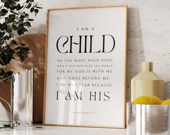 Puede incluir: Una impresión enmarcada con las palabras "I AM A CHILD" en una fuente elegante. El texto continúa con una cita religiosa. El marco es dorado y la impresión se muestra sobre una superficie blanca con elementos decorativos.