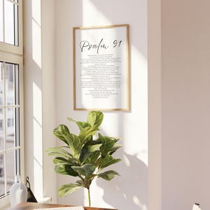 Puede incluir: Un cuadro de pared rectangular vertical que presenta el texto Salmo 91 en una fuente cursiva y serif negra sobre un fondo blanco, encerrado en un marco fino de madera clara. La impresi&oacute;n muestra el pasaje b&iacute;blico completo en letras negras.