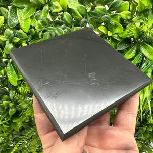 Könnte beinhalten: Ein glatter, schwarzer Obsidian-Kristall, poli auf Hochglanz, in Form eines Quadrats. Der Kristall ist etwa 7,6 cm breit und 7,6 cm lang.