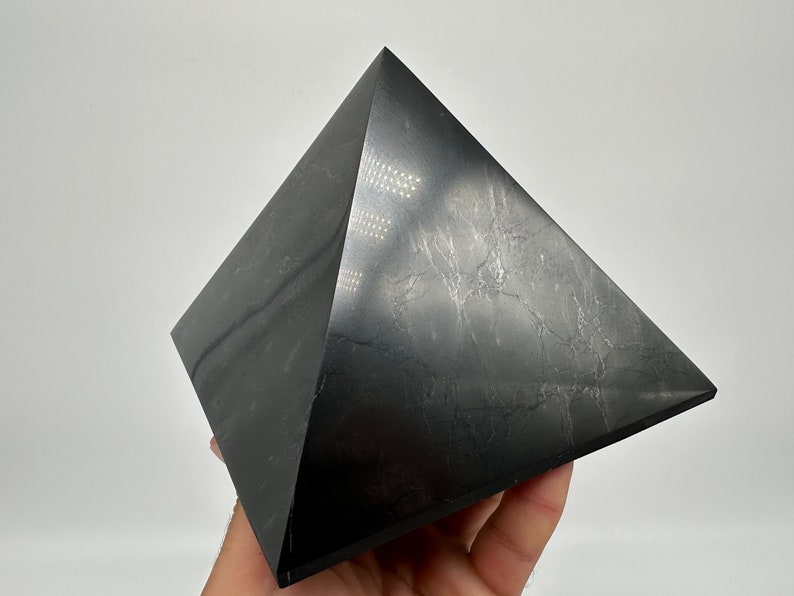 May include: A black obsidian pyramid with a smooth, polished surface. The pyramid has a slightly textured appearance, giving it a unique look.