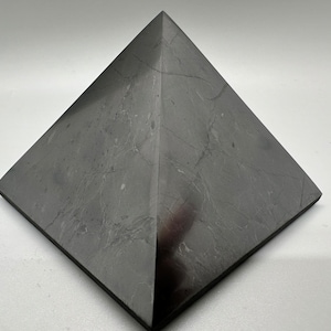 May include: A black pyramid made of polished stone with visible veining.