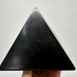 May include: A black obsidian pyramid, a type of crystal used in healing and meditation.