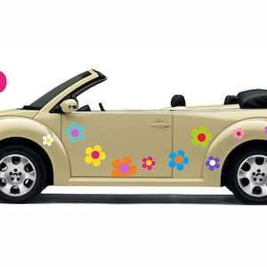 Puede incluir: Un coche descapotable beige decorado con calcomanías de flores de colores. El coche tiene una capota negra y ruedas negras. Las calcomanías de flores son de varios colores, incluyendo rosa, amarillo, azul, naranja y blanco.