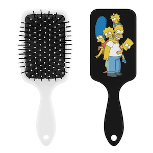 以下が含まれることがあります： 黒いブラシと白と黒のハンドルが付いた2つのヘアブラシ。1つのブラシは白いハンドル、もう1つは黒いハンドルです。黒いハンドルが付いたブラシには、シンプソンズファミリーのグラフィックが描かれています。