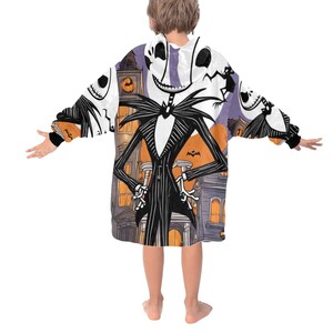 May include: A white hooded sweatshirt with a colorful print of Jack Skellington from the Nightmare Before Christmas movie. The print features Jack Skellington in a suit with a striped pattern, standing in front of a purple and orange background with houses and bats.