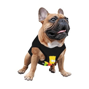 Puede incluir: Un bulldog francés marrón y beige con un tanque negro con un personaje de dibujos animados amarillo en él. El personaje lleva una camisa roja y pantalones verdes.