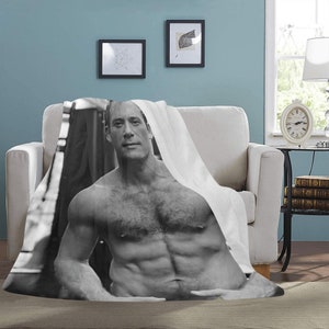 May include: A black and white photo of a shirtless man with a muscular physique. The man is looking directly at the camera. The photo is printed on a white fleece blanket.