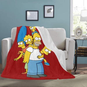 Op de afbeelding: Een rode, witte en gele deken met de Simpsons-familie. Homer, Marge, Bart, Lisa en Maggie zijn afgebeeld in hun iconische cartoon-stijl. De deken is gemaakt van zacht, pluche materiaal en is perfect om een ​​toets van plezier aan elke kamer toe te voegen.