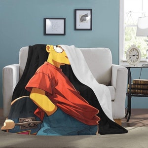Op de afbeelding: Een zwart-witte deken met een cartoonafbeelding van een geel personage dat een rood shirt en een blauwe spijkerbroek draagt en een skateboard vasthoudt. Het personage heeft een geel hoofd met zwart haar en een zwarte omtrek.
