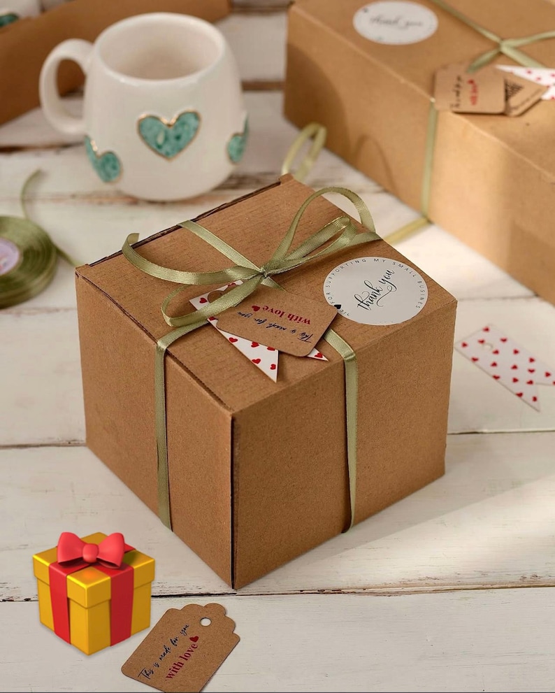 May include: A square brown cardboard gift box tied with a sage green ribbon. A round white sticker reads "thank you for supporting my small business" and a brown paper tag reads "This is made for you with love" with a small red heart icon.