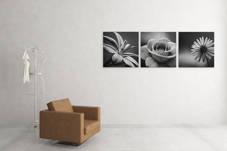 May include: Three black and white canvas prints of flowers. The prints are arranged horizontally on a white wall. The first print shows a lily, the second print shows a rose, and the third print shows a daisy.