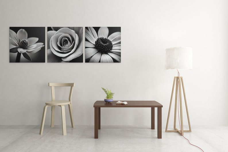 May include: A white chair with a wooden frame sits next to a brown coffee table with a small potted plant on top. A white lamp with a wooden tripod base stands in the corner of the room. Three black and white flower photographs hang on the wall.