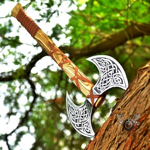 May include: A double-headed axe with a wooden handle wrapped in brown leather. The axe heads are decorated with intricate Celtic knotwork designs. The axe is resting on a tree trunk.