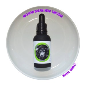 Pode incluir: Uma garrafa de tintura preta com conta-gotas, rotulada "Mexican Dream Herb Tincture" e um gráfico de macaco. A garrafa está em um prato redondo branco. O texto "Herbal Monkey" também é visível.