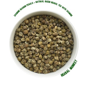 May include: A white bowl filled with green jasmine dragon pearls tea. The tea is labelled "Jasmine Dragon Pearls - Natural Green Herbal Tea with Jasmine" and "Herbal Monkey".