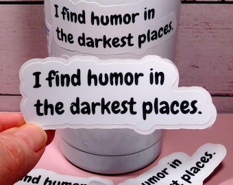 May include: White stickers with the phrase "I find humor in the darkest places" in black text. The stickers are in a cloud shape. Some stickers are on a white tumbler, and others are held by a hand.