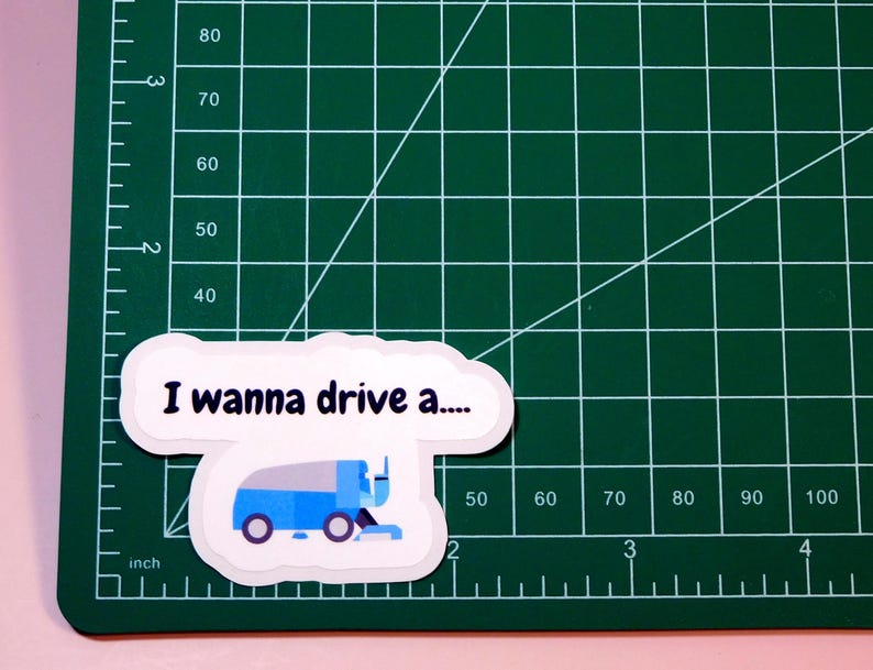May include: A white sticker with a blue and white cartoon image of a street sweeper and the text "I wanna drive a..."