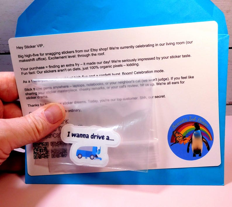 May include: A blue envelope with a white card inside. The card has a message about stickers and a small plastic bag with a sticker inside. The sticker is a blue and white cartoon image of a street sweeper with the text "I wanna drive a..." printed on it.