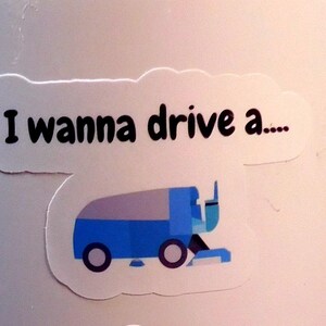 May include: A white sticker with the text "I wanna drive a..." and a blue and gray cartoon illustration of a snowplow.