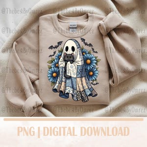 May include: Beige sweatshirt with a Halloween-themed graphic. The design features a ghost holding a black cat, surrounded by blue flowers and bats. The ghost is wearing a patchwork quilt. The text "PNG | DIGITAL DOWNLOAD" is at the bottom.