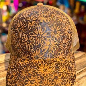 May include: A brown and tan baseball cap with a floral pattern. The cap is made of a mesh material and has a curved brim.