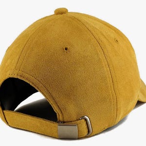 May include: A mustard yellow suede baseball cap with an adjustable strap.